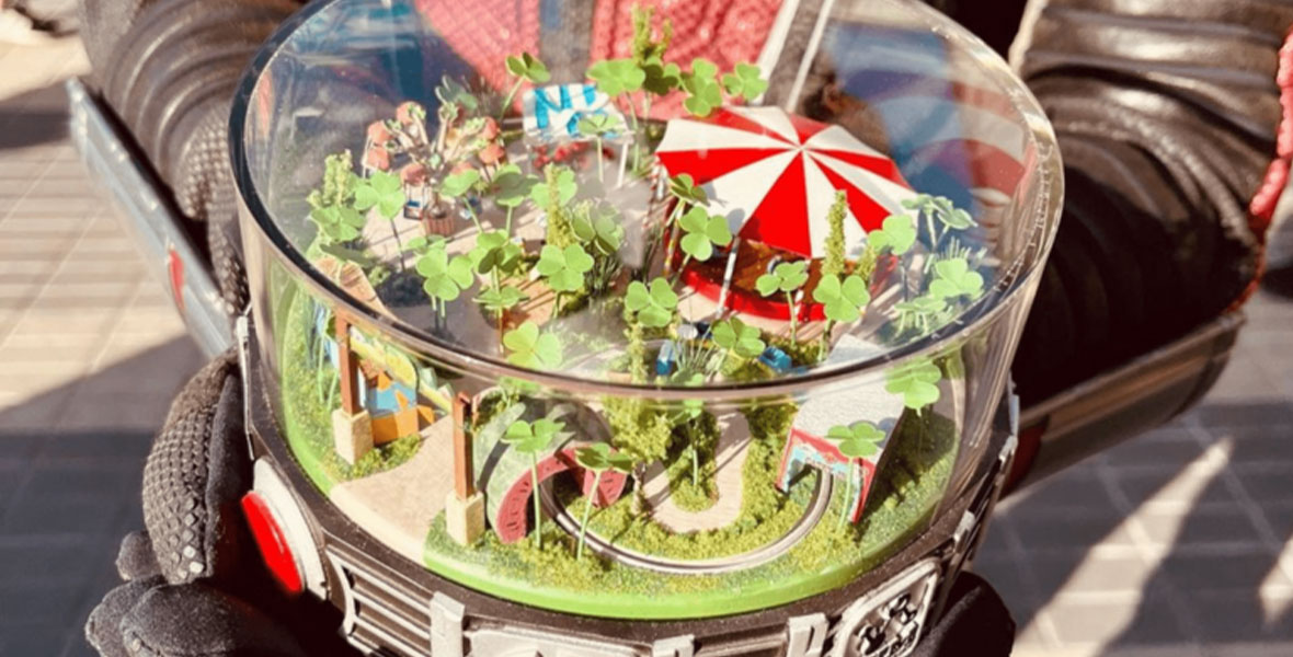 A tiny theme park enclosed in a circular case rests in Ant-Man’s black gloved hands at Avengers Campus in Disney California Adventure