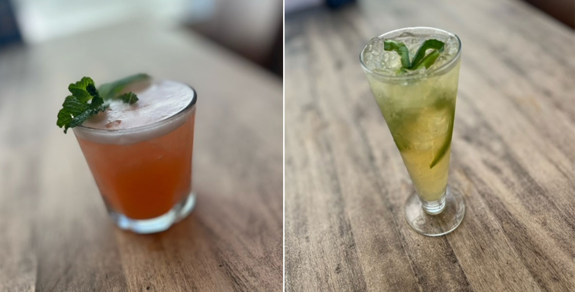 Side-by-side image of Naples Ristorante e Bar’s Galaxy cocktail, in a short glass with a reddish drink featuring a sprig of green mint sitting atop, set on a wooden table; and Green Moon cocktail, in a tall glass with a light green drink featuring a garnish of lime and green pepper, also set on a wooden table. 