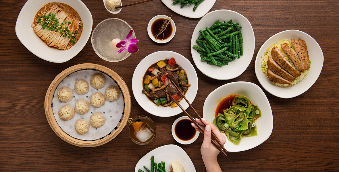 A selection of food offerings from the Din Tai Fung restaurant, arranged on a wooden table and viewed from above.