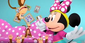 Minnie Mouse, wearing a hot pink and teal workout outfit, points excitedly in a colorful room full of monkeys.