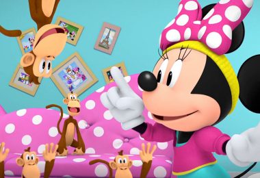 Minnie Mouse, wearing a hot pink and teal workout outfit, points excitedly in a colorful room full of monkeys.