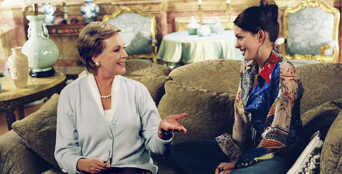 : Disney Legend Julie Andrews and Anne Hathaway sit on a couch in Disney’s The Princess Diaries 2: Royal Engagement. 
