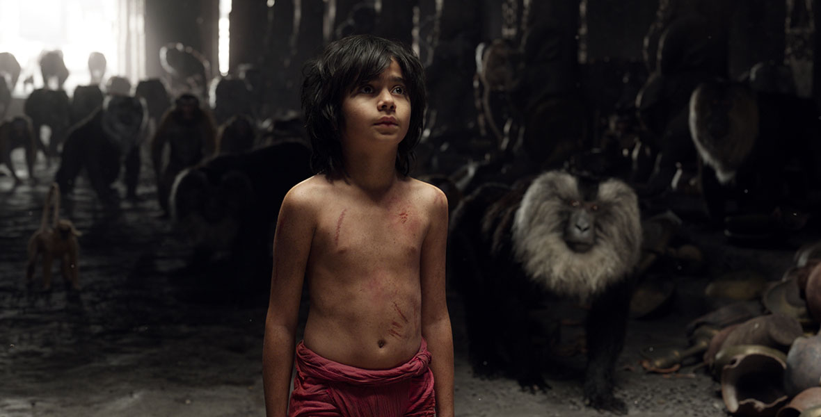 Mowgli (Neel Sethi) huddles inside a cave full of baboons in the live-action adaptation of The Jungle Book.