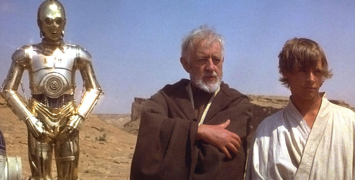 C-3PO, Obi-Wan Kenobi and Luke Skywalker stand on the sands of Tatooine in a still from Star Wars: A New Hope.
