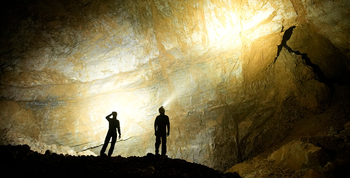 Team members inside Cheve Cave examine a massive borehole.