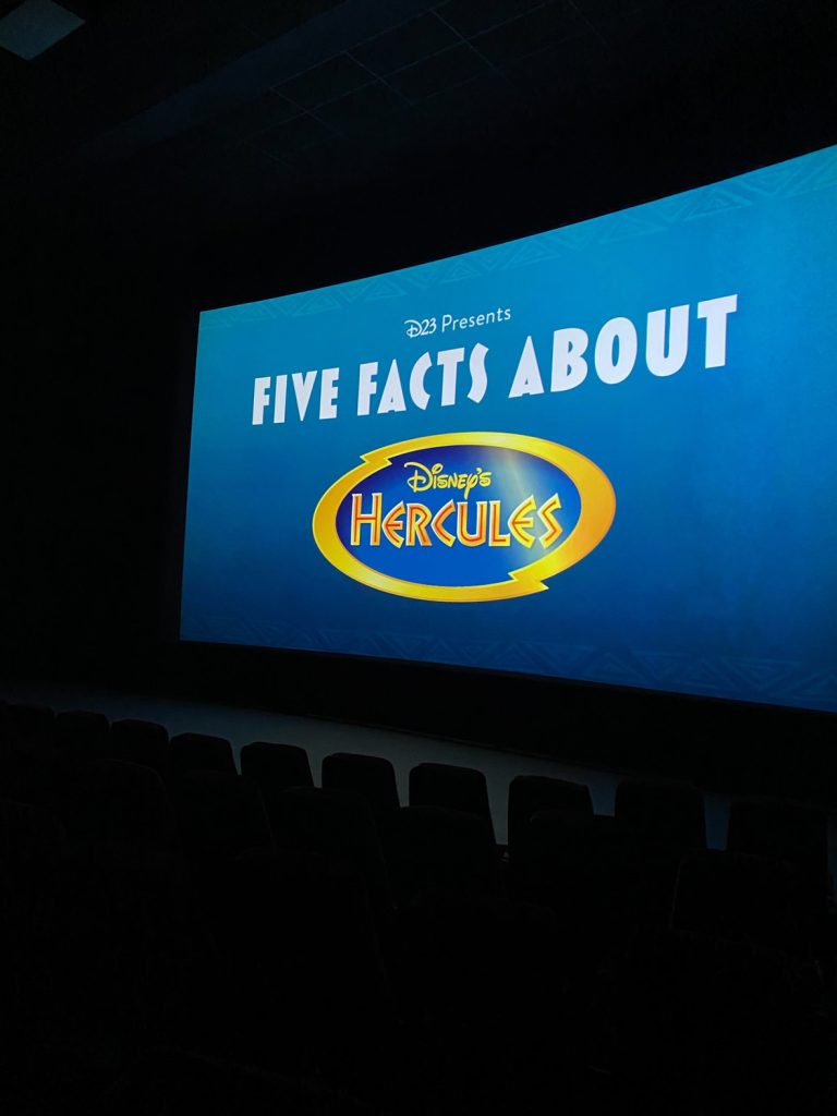 The movie screen shows the title card for “Five Facts About Hercules” in while text on a blue background.