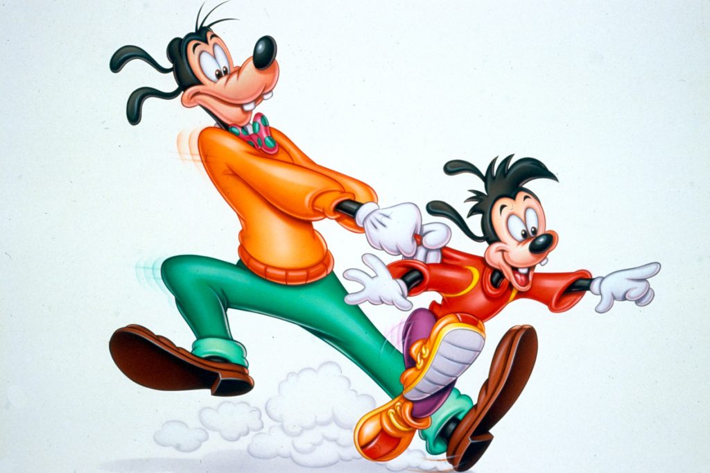 In a still from Goof Troop, Goofy is wearing an orange shirt, polka dot bow tie, and green pants, and his son Max is wearing a red shirt and purple pants. Goofy is holding onto Max’s shirt as Max tries to run away.