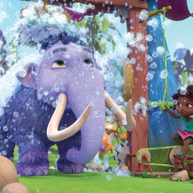 A large purple woolly mammoth stands under a shower head and is surrounded by bubbles. A young girl operates the shower while standing on a stool in Disney Junior’s animated series Eureka!