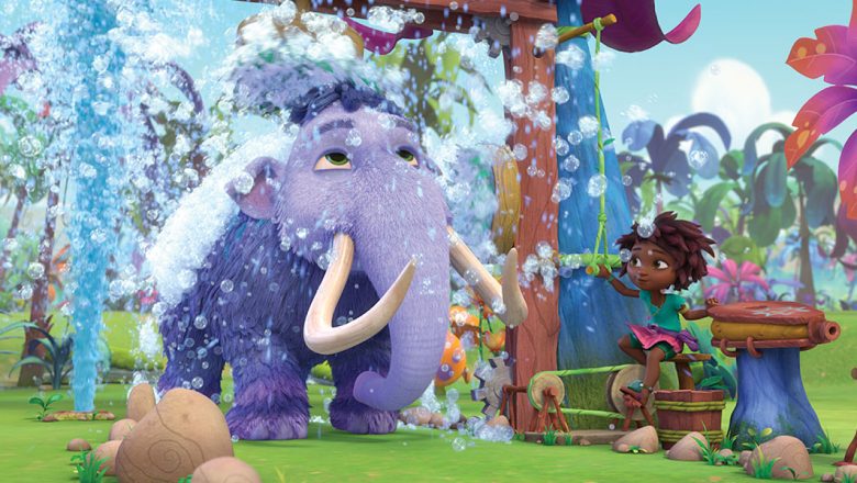 A large purple woolly mammoth stands under a shower head and is surrounded by bubbles. A young girl operates the shower while standing on a stool in Disney Junior’s animated series Eureka!