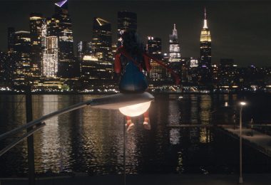 Iman Vellani as Ms. Marvel, aka Kamala Khan, sits atop a glowing streetlight as she surveys Manhattan in the distance