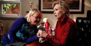 (Left to right) Becky Jackson (Lauren Potter) and Sue Sylvester (Jane Lynch) make a public address announcement to McKinley High School from the principal’s office during an episode of Glee.