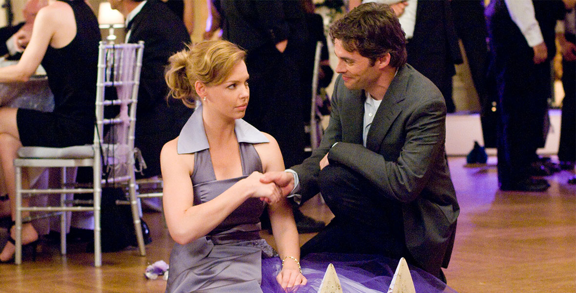 (Left to right) Jane (Katherine Heigl) and Kevin (James Marsden) shake hands as she sits on the floor frowning in a lilac bridesmaid dress in the movie 27 Dresses.