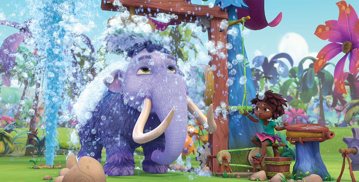 A still from the animated series Eureka! featuring a large purple woolly mammoth being washed with an outdoor shower crafted by Eureka (voice by Ruth Righi), who stands on a step stool.