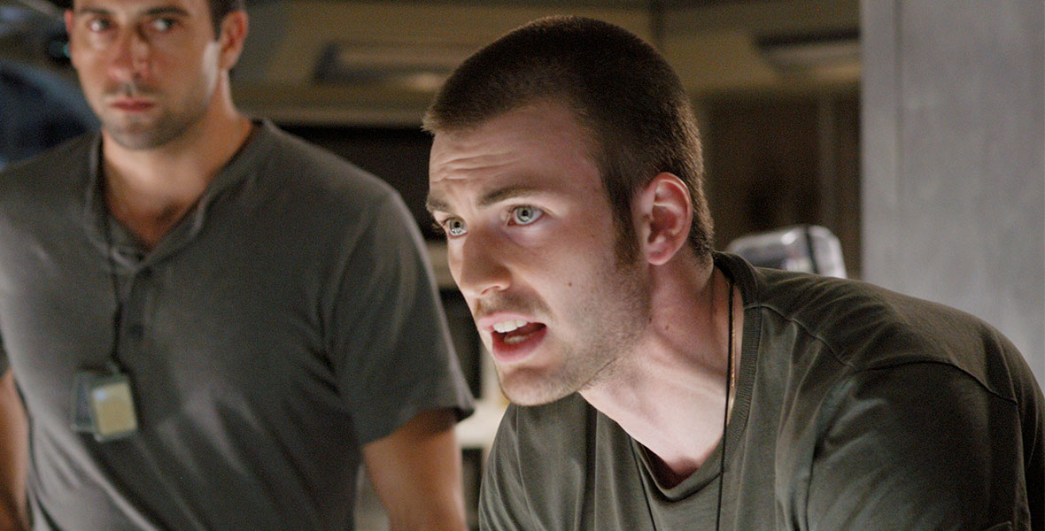 Chris Evans, with a buzzed head and a green shirt, has a tense conversation as engineer James Mace in scene from Sunshine.