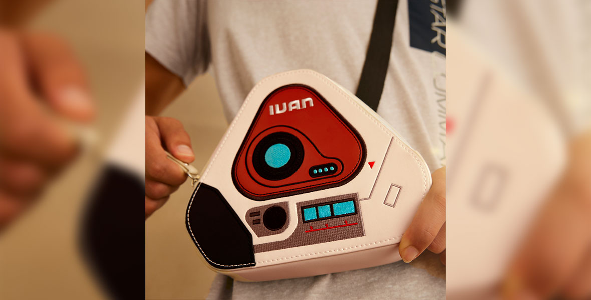 A white, triangular belt bag with an illustration of the spaceship computer IVAN from the film Lightyear.