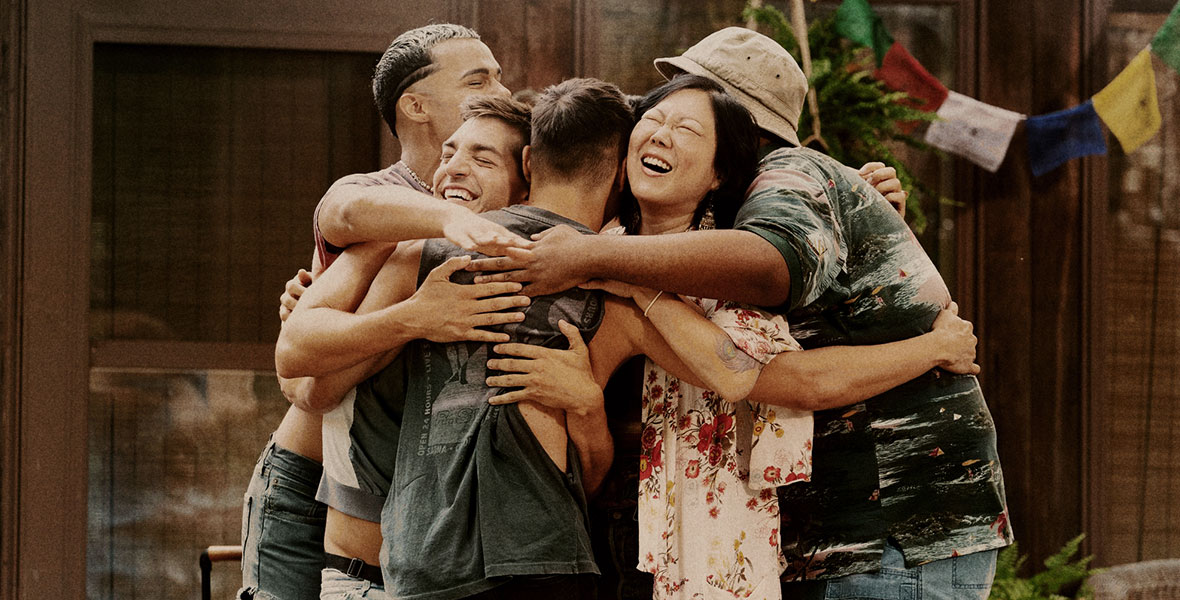 The cast of Searchlight Pictures’ Fire Island embrace with a group hug.