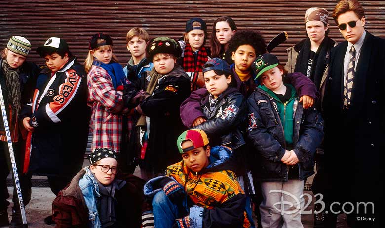 Emilio Estevez, who stars in The Mighty Ducks, stands in sunglasses and office attire with the cast of relative newcomers try to look tough.