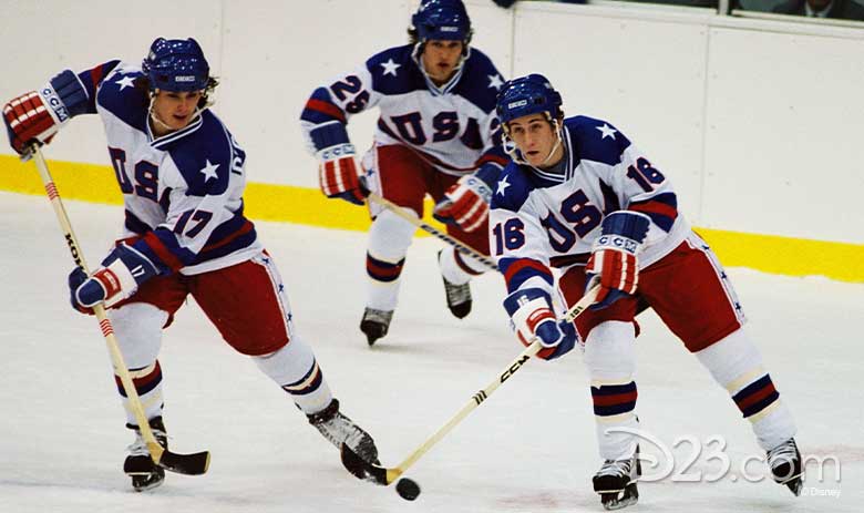 A stirring mid-action scene showcases three members of the 1980 Winter Olympics men’s hockey team on the ice with the puck in their possession.