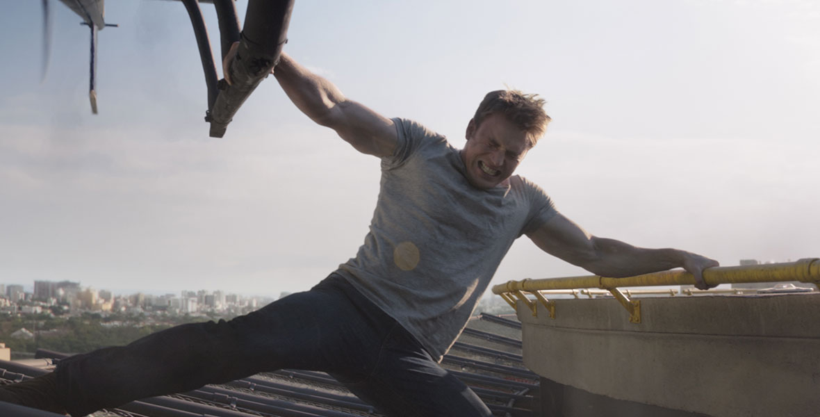 Wearing a gray T-shirt and gritting his teeth in Captain America: Civil War, Chris Evans’ Steve Rogers aka Captain America flexes his biceps as he tries to stop a helicopter from escaping. He grabs a yellow banister atop a building with his left hand, and with his right hand, he grabs onto the helicopter.