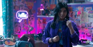 Iman Vellani as Kamala Khan stands at the ready in her colorfully decorated bedroom at her family home in Jersey City.