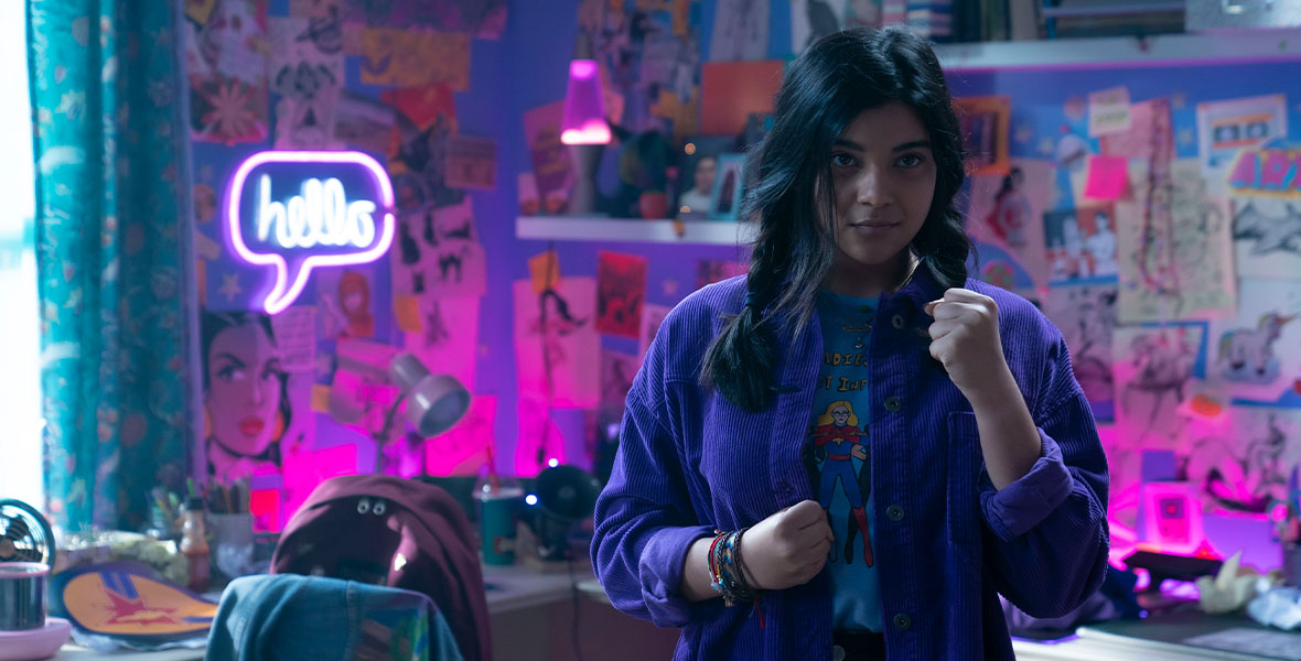 Iman Vellani as Kamala Khan stands at the ready in her colorfully decorated bedroom at her family home in Jersey City.