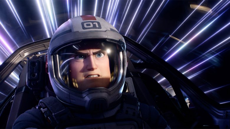 Still of Buzz Lightyear in the cockpit of a spaceship from Disney and Pixar’s Lightyear. He is wearing a helmet, and there are blue, purple, and white streaks of light seen behind him.