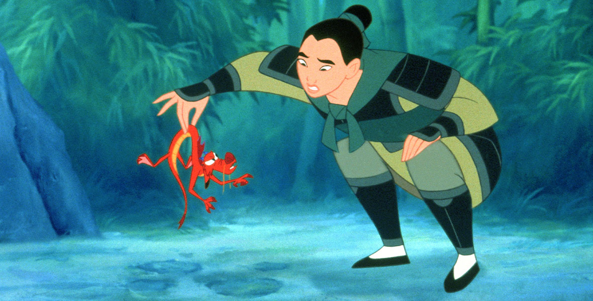 Mushu (voiced by Eddie Murphy), a small red and orange dragon, looks up as Mulan (voiced by Disney Legend Ming-Na Wen) holds him in her fingertips as she looks at him perplexed in the animated feature film Mulan.