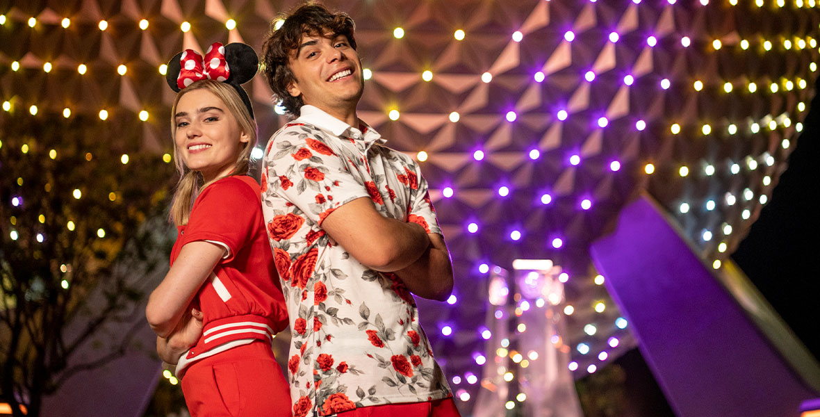 Meg Donnelly and Pearce Joza stand back-to-back in front of Starship Earth at EPCOT.