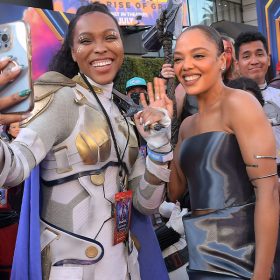 A cosplayer dressed as Valkyrie holds an iPhone in her hand and snaps a selfie with actress Tessa Thompson, who wears a strapless metallic dress at the world premiere of Marvel Studios’ Thor: Love and Thunder.