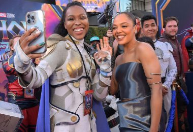 A cosplayer dressed as Valkyrie holds an iPhone in her hand and snaps a selfie with actress Tessa Thompson, who wears a strapless metallic dress at the world premiere of Marvel Studios’ Thor: Love and Thunder.