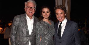 Left to right: Disney Legend Steve Martin, wearing a grey plaid suit jacket; Selena Gomez, wearing a sparkly silver evening gown; and Martin Short, wearing a dark grey suit, standing together at the premiere of Hulu’s Only Murders in the Building season 2.