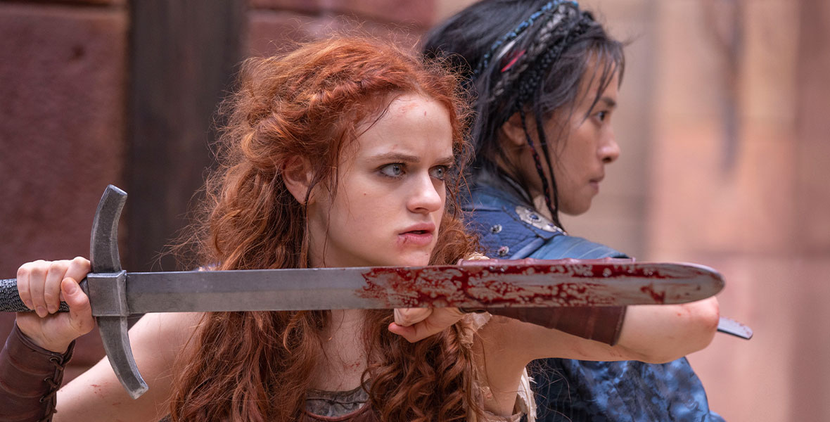 Joey King and Veronica Ngo stand back-to-back with swords in their hands near a doorway waiting to fight intruders in 20th Century Studios’ The Princess