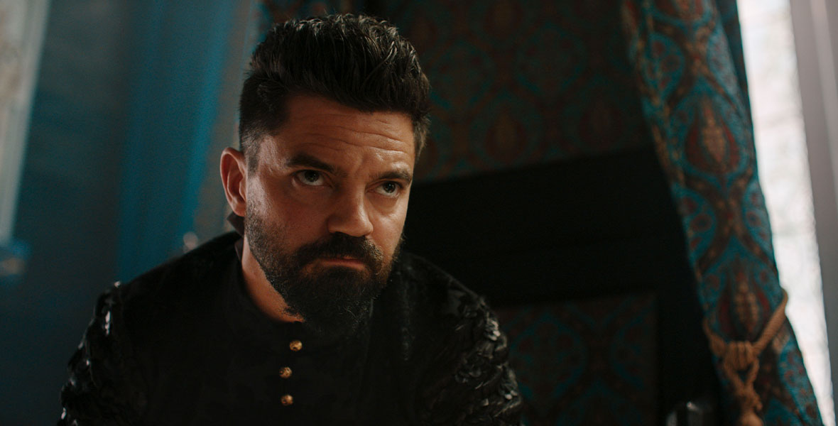 Dominic Cooper, who stars in 20th Century Studios’ The Princess, wearing medieval clothing and sitting in a dark room.