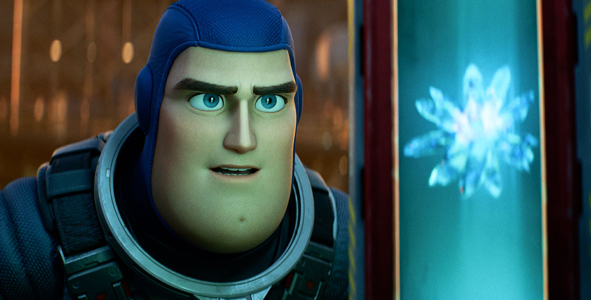 In this scene from Lightyear, Buzz Lightyear (voiced by Chris Evans) is wearing a purple cowl and is examining a special crystal that is emitting a blue light.