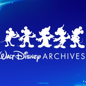 The Walt Disney Archives logo, which features 5 silhouettes of Mickey Mouse each drawing the next Mickey, along with text below them reading, "Walt Disney Archives." The logo is against a blue gradient background with light blue sparkles, lens flares, and light leak in the upper left and lower right corner.