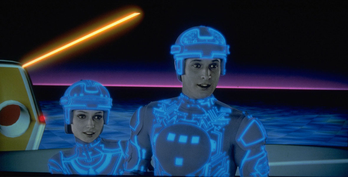 Cindy Morgan and Bruce Boxleitner as Lora and Alan in TRON. The pair are in the grid and wearing illuminated blue light suits.