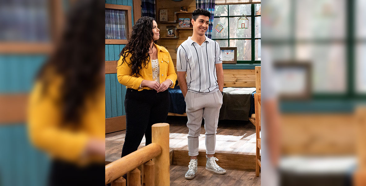 Actress Miranda May looks at actor Trevor Tordjman while standing in a rustic cabin. 