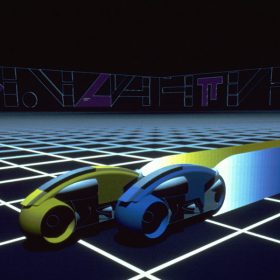 An image from the original 1982 TRON featuring two light cycles racing on the grid. One is yellow and slightly ahead of a blue light cycle next to it.