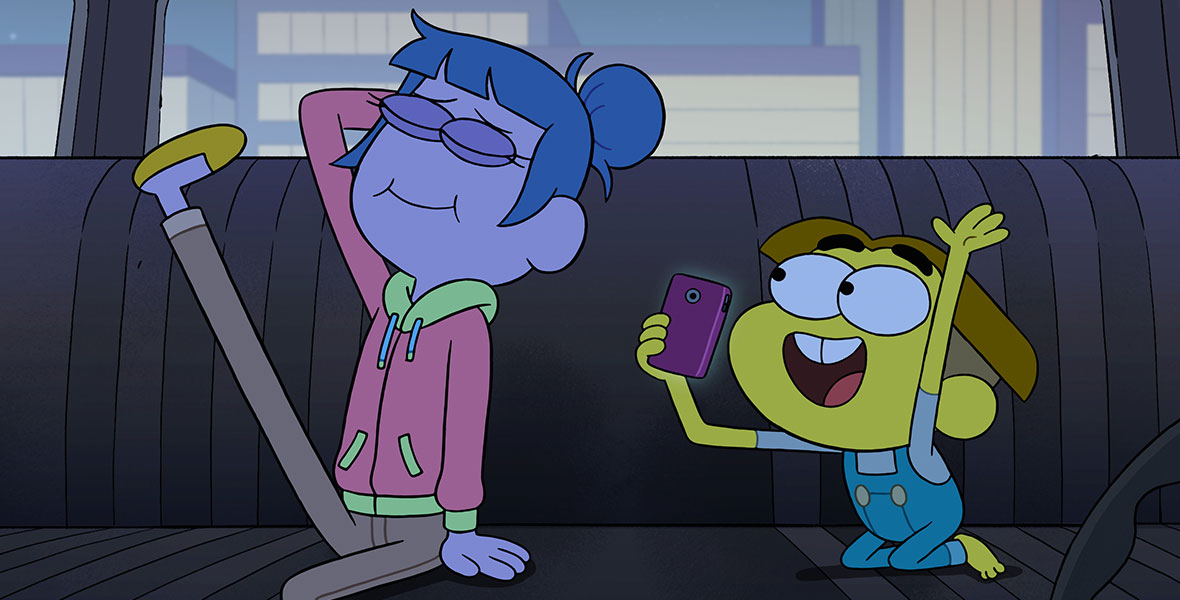 A young woman with blue hair and purple skin poses for a young boy holding a cell phone with one of her legs kicked up to the car’s ceiling.