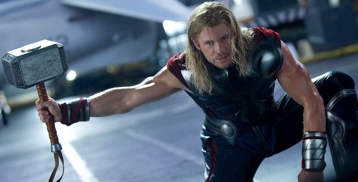 Thor crouches on one knee in his armor extending his right arm holding onto his hammer, Mjolnir.