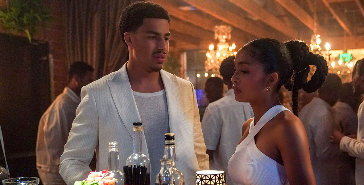 (L-R) Actor Marcus Scribner and Actress Yara Shahidi stand next to each other near a small bar, wearing all-white clothing at a white-themed party.