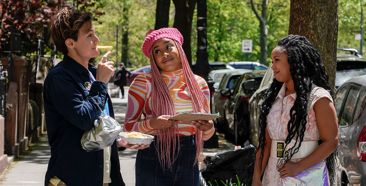 (L-R) Actors Moses Storm, Phoebe Robinson, and Toccarra Cash talk on the sidewalk of a treelined street.