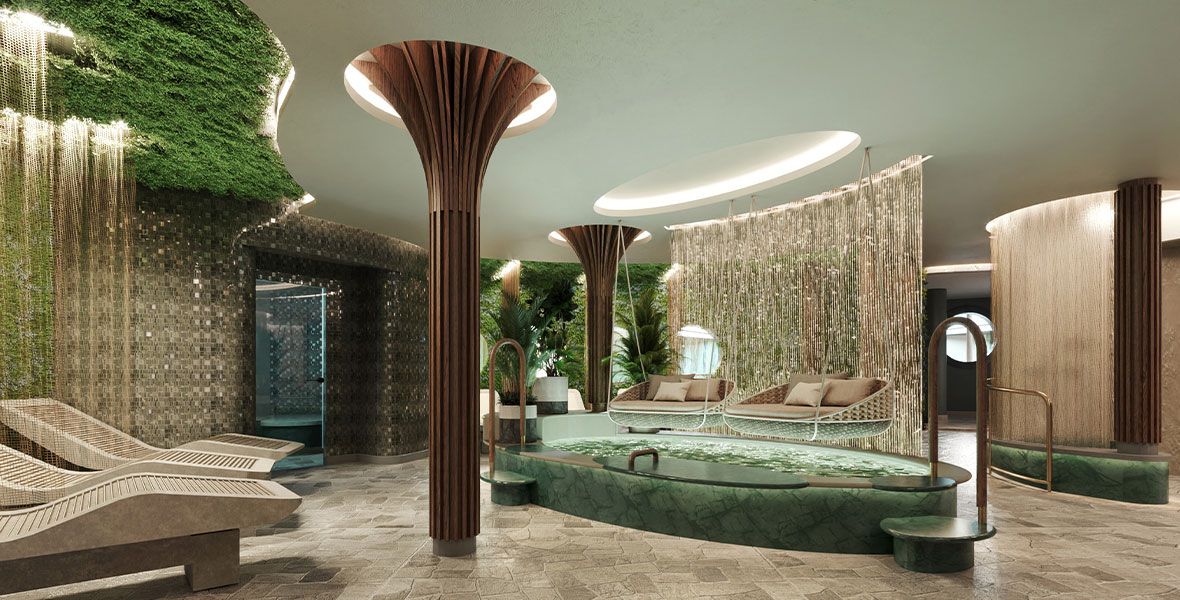 The spa aboard the Disney Wish is themed after the calming waterfalls of rainforests with soothing green plants on a wall, beige tile, and a large tub.