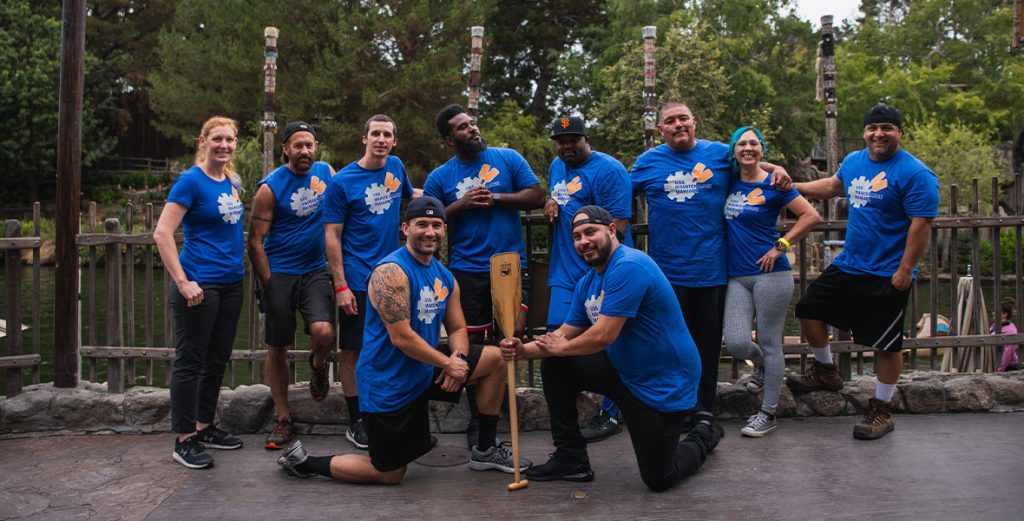 Members of the “USS Maintenance Maniacs” wearing matching blue team shirts, pose with an oar on the dock of the Rivers of America early in the morning after completing their time trials in the Disneyland Canoe Race event.