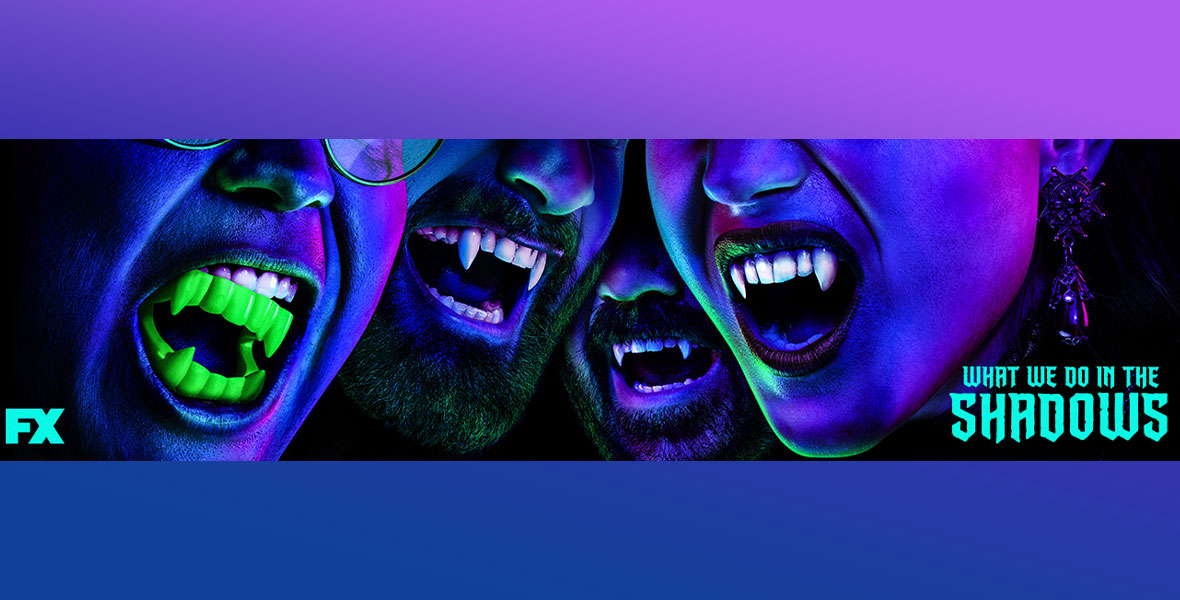 A promotional banner for What We Do in the Shadows on FX. The image is bathed in a purple glowing light and features the bottom half of the faces of four characters, three of which are vampires and one which is a human wearing fake, neon green vampire teeth. The human character is on the far left and his fake teeth are falling out of his mouth. In the middle are two men with beards baring their fangs. On the far right is a woman also showing her fangs and wearing an ornate earring. The show’s title is written in the bottom right corner in cyan font.