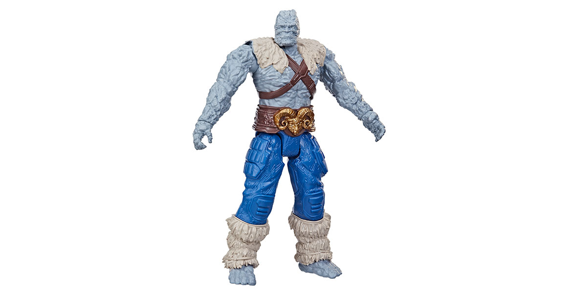 An action figure of of Korg, a grey rock monster wearing blue pants, a brown belt with a golden ram belt buckle, and white fuzzy leg wraps and cape.
