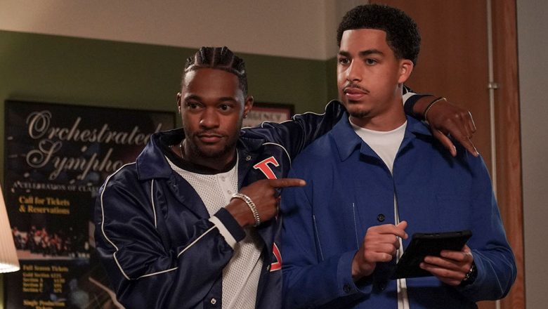 Left to Right) Actor Christopher Meyer wraps his left arm around actor Marcus Scribner and gestures with his right arm pointing to Scribner’s chest.