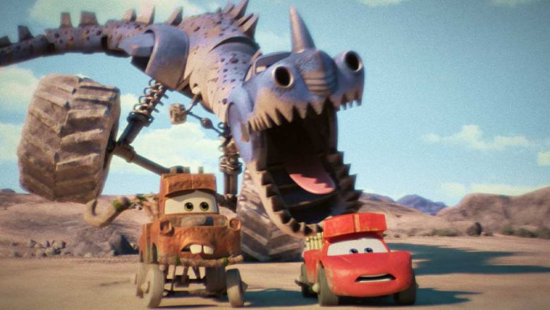 In an image from the Disney+ series Cars on the Road, the brown tow truck Mater is on the left and the red sports car Lightning McQueen is on the right. They’re being chased by some sort of purple dinosaur-car hybrid with large wheels through a desert landscape.