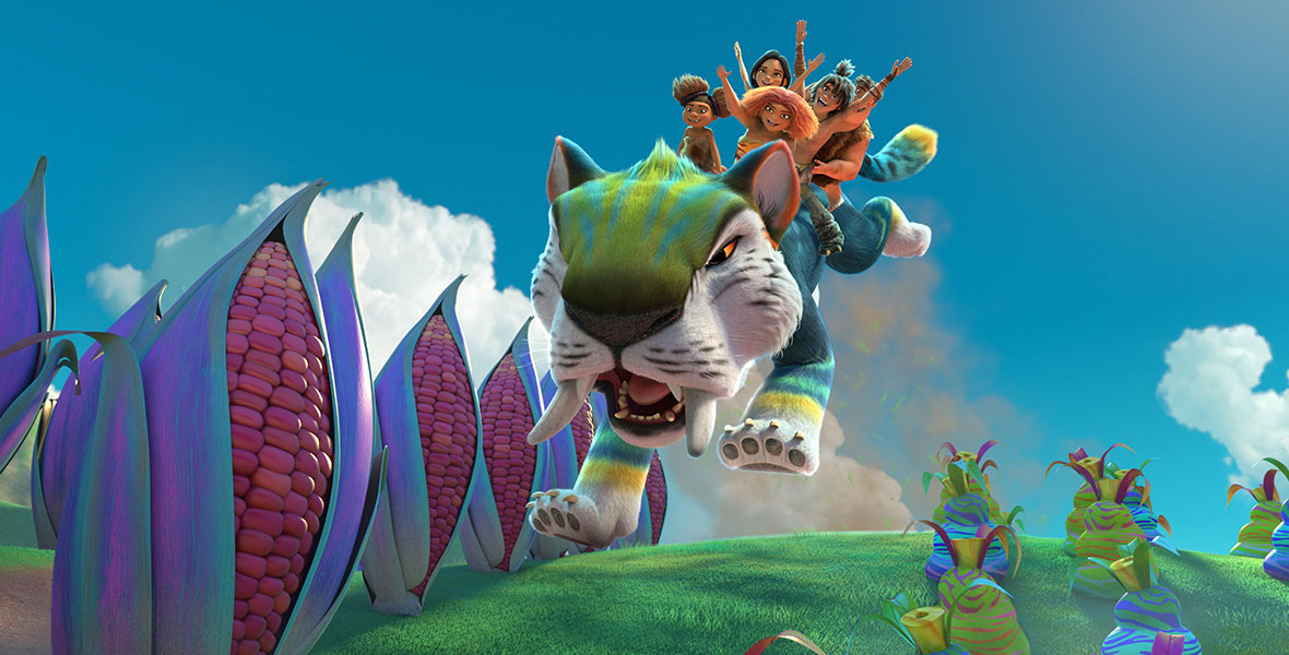 Animated prehistoric people ride a large, boldly colored tiger through the jungle. Behind them is a bright blue sky with fluffy white clouds. The adjacent foliage is large and multi-colored.