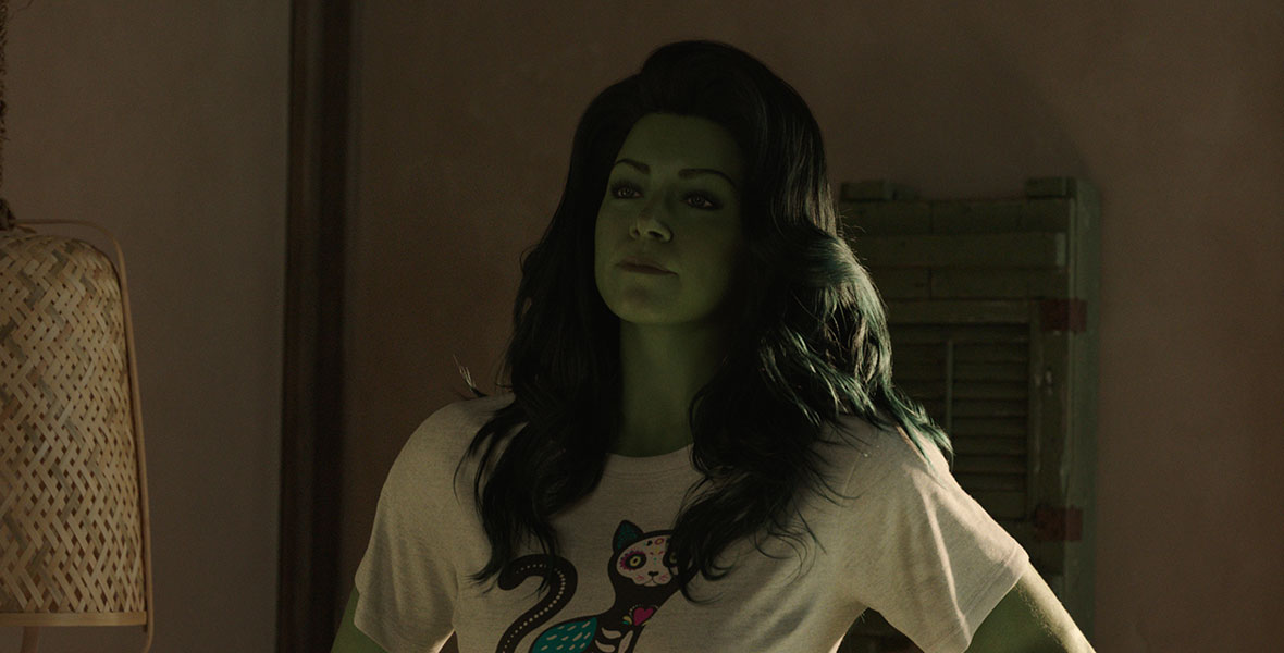 Actor Tatiana Maslany portrays Jennifer Walter/She-Hulk with CGI green skin and hair and a graphic t-shirt.